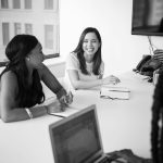 Group of women discussing ideas in a corporate office room.