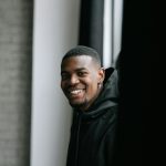 Portrait of a smiling man indoors with natural light and soft tones.