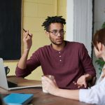 Two colleagues engaged in a collaborative discussion during a team meeting at the office.