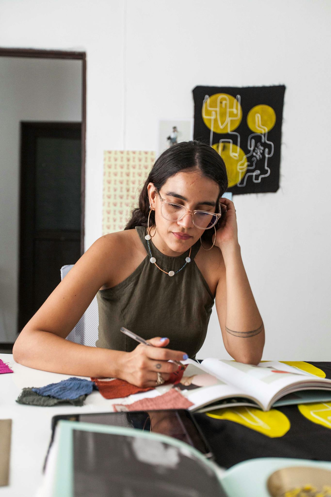 Young woman designer working thoughtfully with fabric swatches at studio.